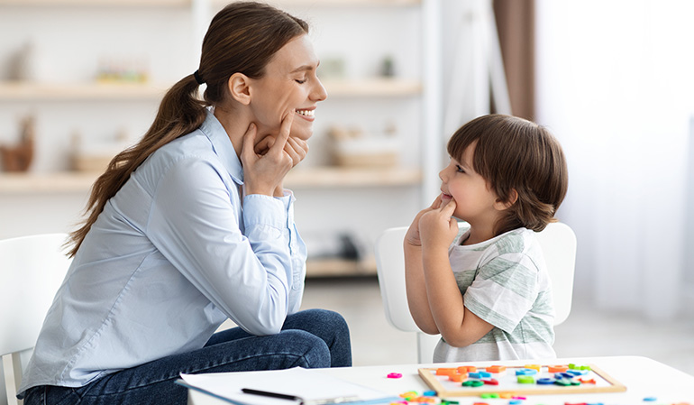 Child practicing speech therapy exercises with a therapist to improve communication skills