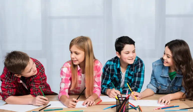 Four diverse young students collaborating and drawing together during a creative session at an after school program.