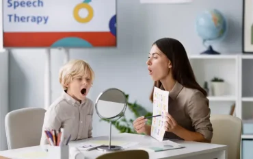 Speech therapist helping a child practice expressive and receptive language skills using a mirror during a speech therapy session
