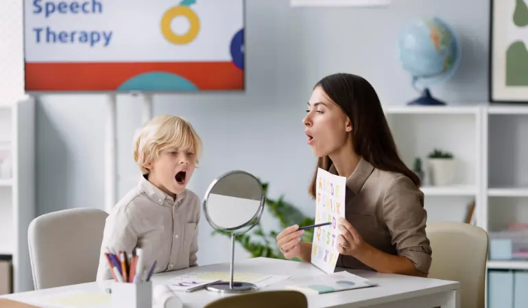 Speech therapist helping a child practice expressive and receptive language skills using a mirror during a speech therapy session