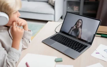 Child attending an online speech therapy session on a laptop with a speech therapist