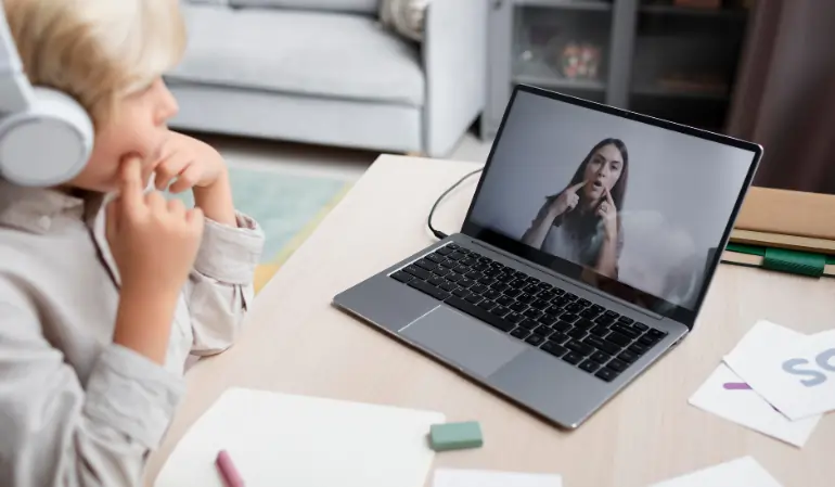 Child attending an online speech therapy session on a laptop with a speech therapist