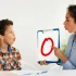 Speech therapist conducting a communication and language assessment with a child at a child assessment center using visual learning tools.