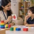 Best treatment for ADHD shown through a warm child development assessment, with a female therapist engaging a young child using colorful toys and picture cards in a supportive Kerala setting