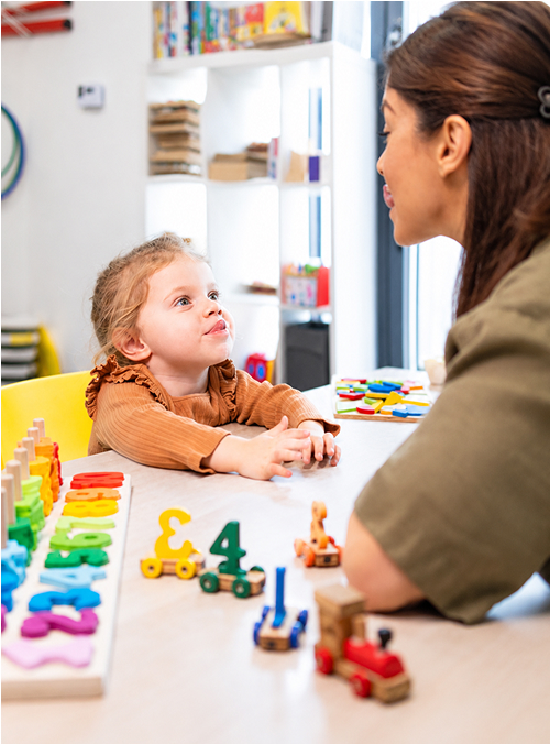 Young child interacting with a therapist during a playful learning activity with colorful educational toys.