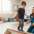 Young boy balancing with beanbags on a wooden beam while a pediatric occupational therapist watches during an ADHD and occupational therapy session.