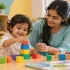 Early childcare development activities with a toddler stacking blocks beside a therapist at a childhood development center